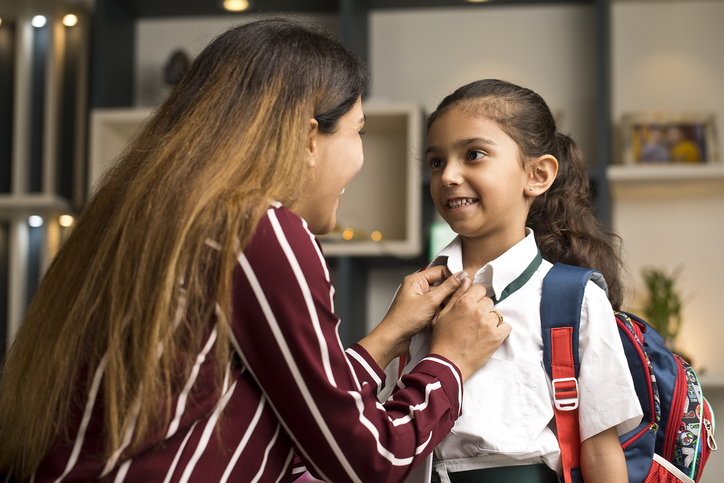 Loving mother getting her daughter ready for school at home