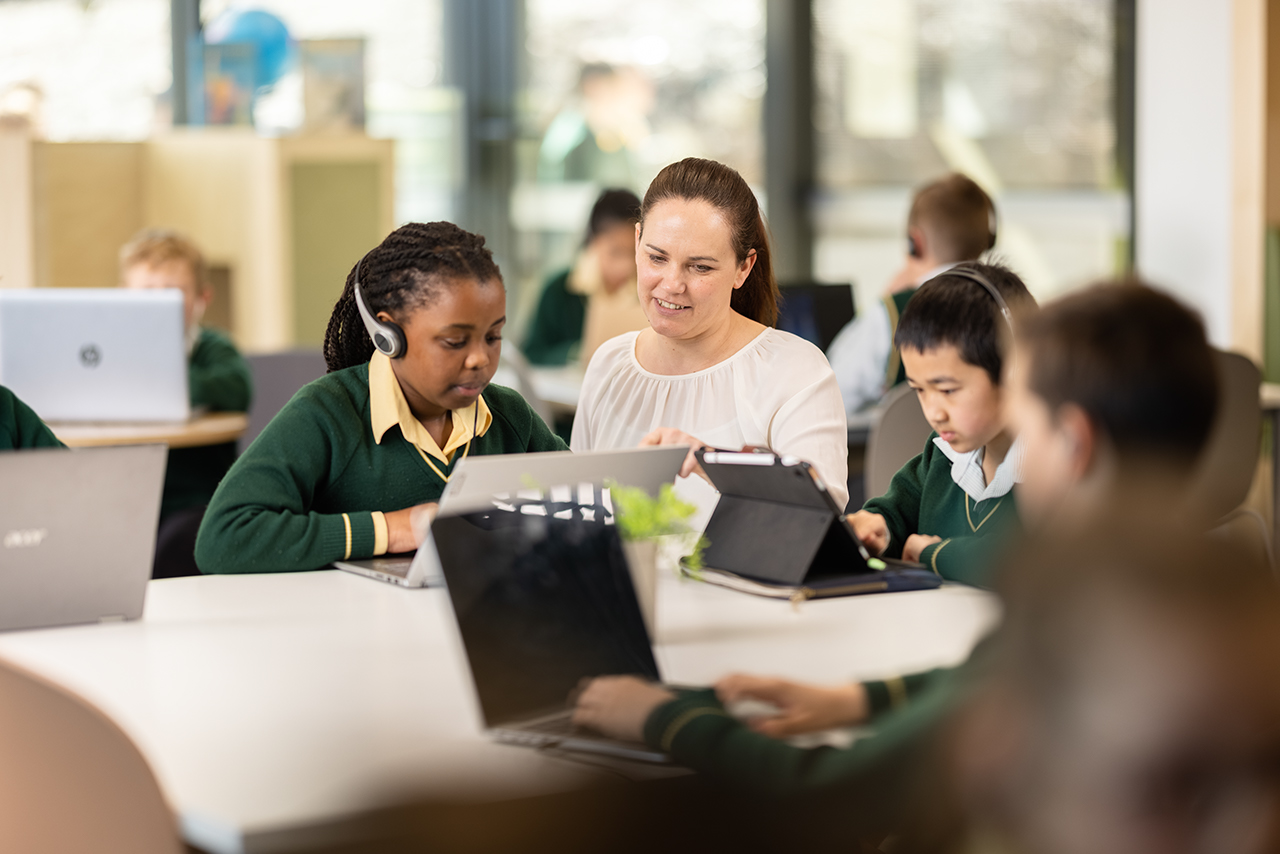 teacher teaching students on laptops