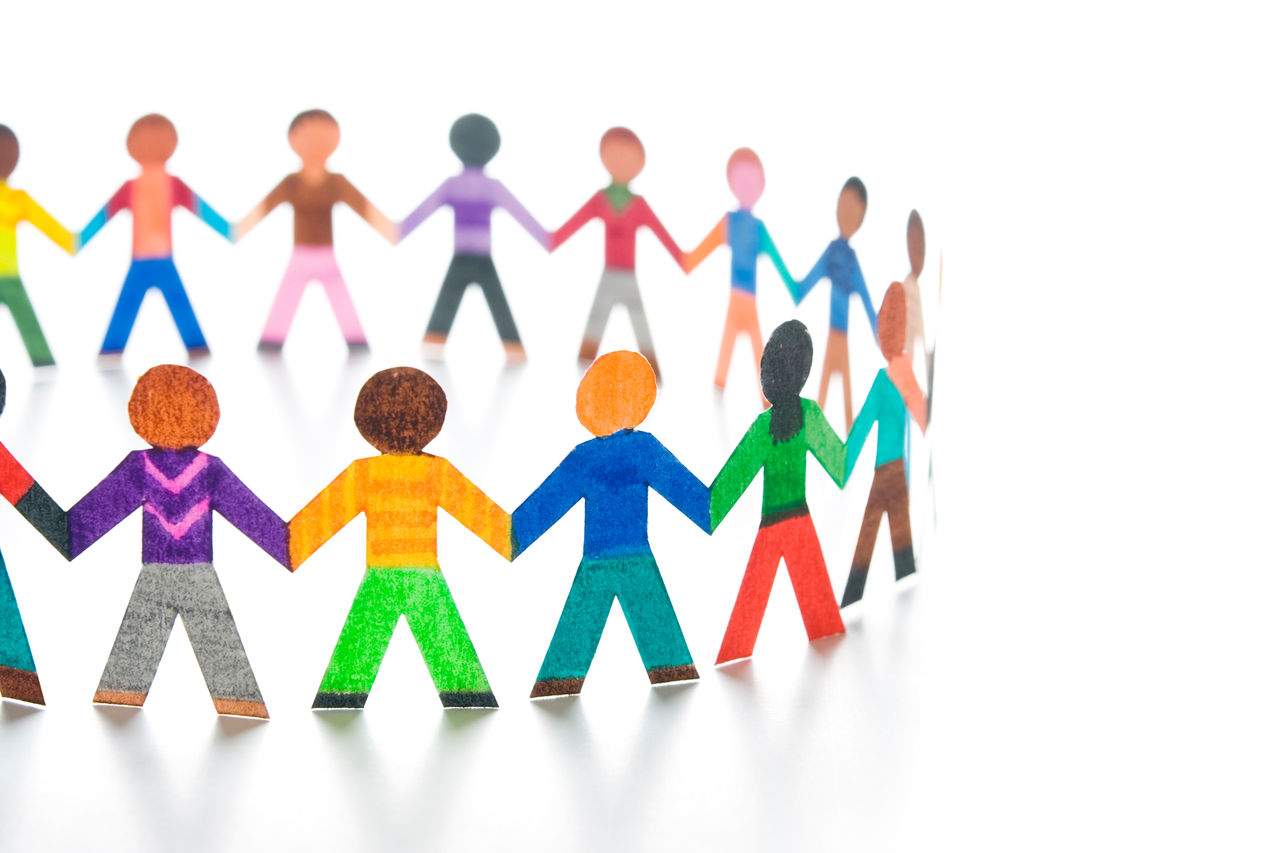 One-half of a large circle of paper people on a reflective surface.